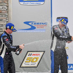 James and Devin with champagne on podium - BimmerWorld Racing Charges to Podium in MICHELIN Pilot Challenge Race at Sebring