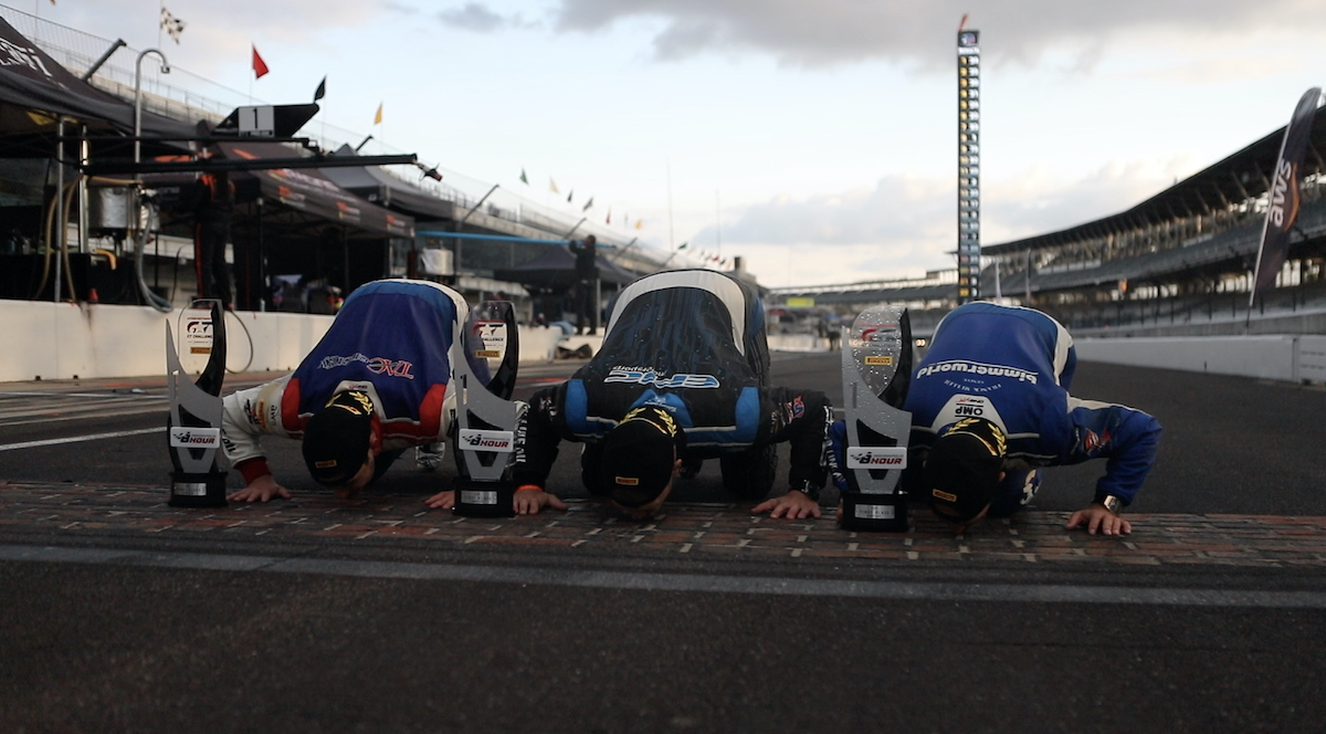 BimmerWorld drivers kissing the bricks at Indy after winning the 8-hour endurance race